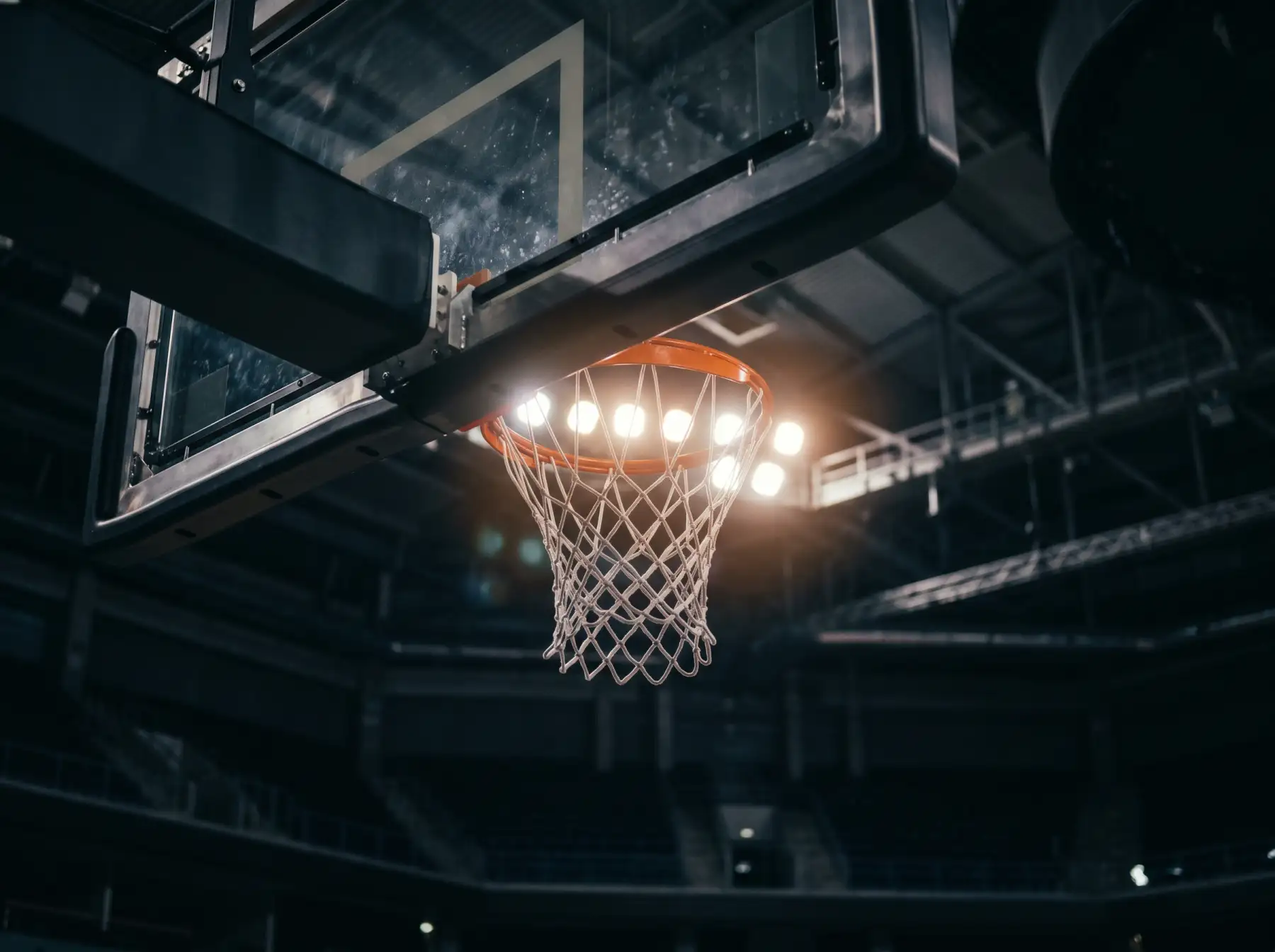 Aro de baloncesto con red a contraluz en un pabellón durante un partido